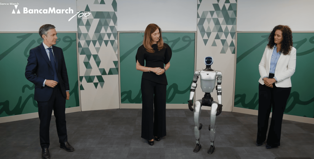 Tres directivos de Banca March junto a un robot humanoide en un plató hablando de la IA.